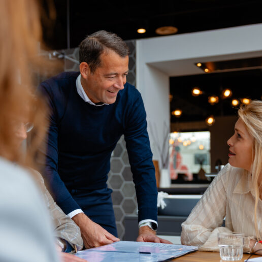 Collega staat naast tafel en heeft overleg